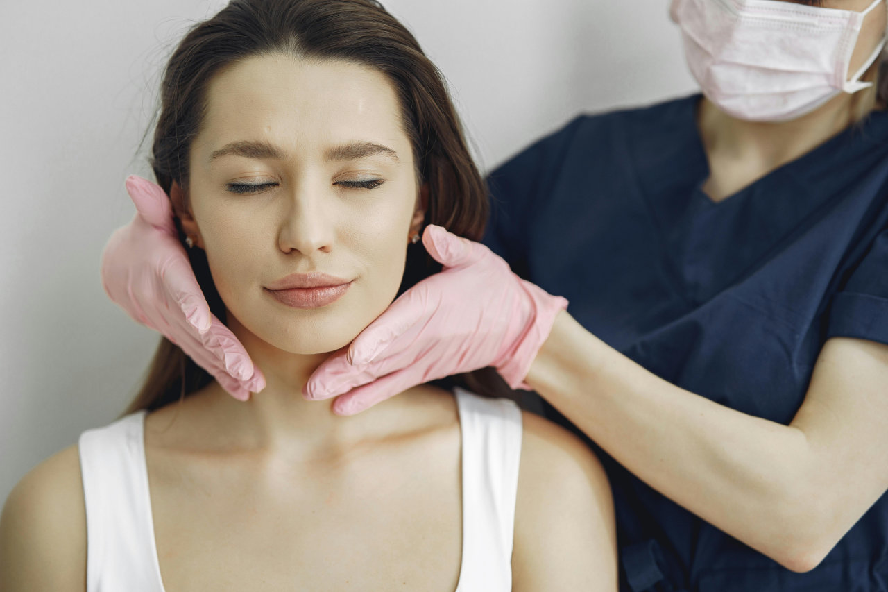 Stručnjak sa maskom i rukavicama pregleda lice žene u ordinaciji